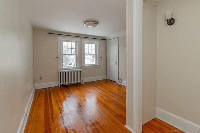 empty room with hardwood / wood-style flooring and radiator