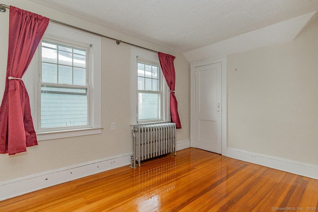 spare room featuring hardwood / wood-style floors and radiator heating unit