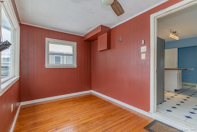 spare room featuring crown molding, light hardwood / wood-style flooring, and wood walls