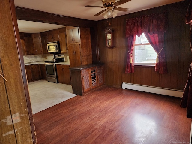 kitchen with a baseboard radiator, ceiling fan, light hardwood / wood-style floors, and appliances with stainless steel finishes