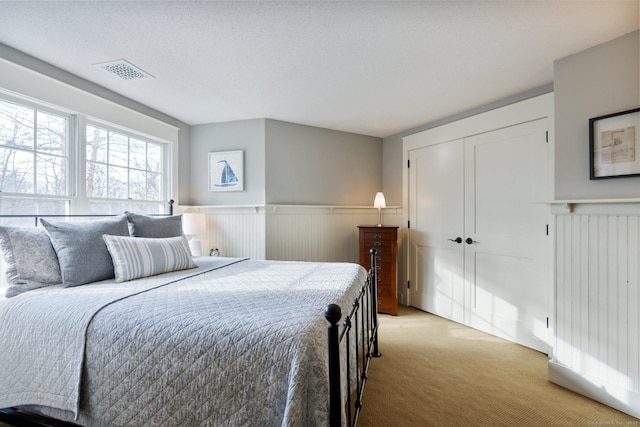 bedroom with a textured ceiling, light carpet, and a closet