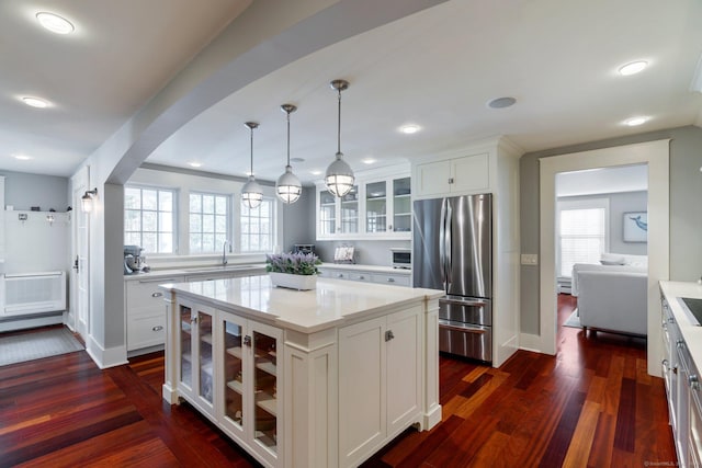 kitchen featuring stainless steel fridge, dark hardwood / wood-style flooring, a center island, white cabinetry, and hanging light fixtures