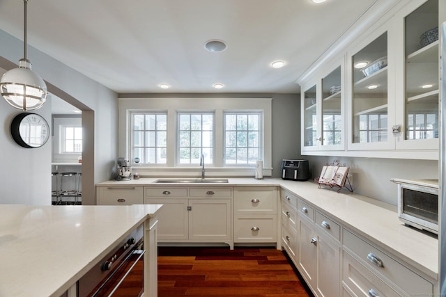 kitchen featuring dark hardwood / wood-style flooring, sink, white cabinetry, and hanging light fixtures