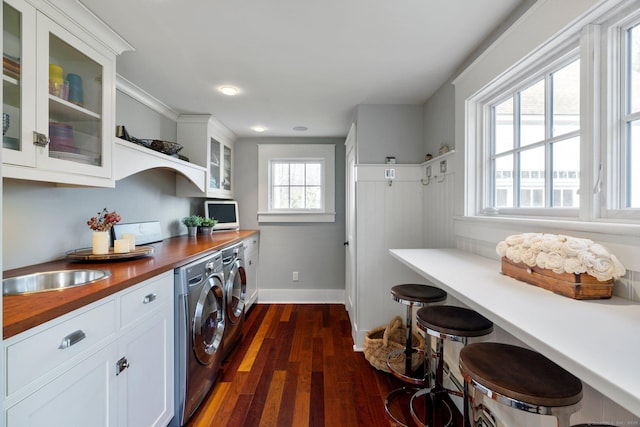 laundry area with cabinets, washing machine and dryer, dark hardwood / wood-style floors, and sink