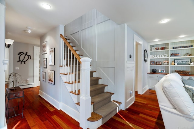 stairs with wood-type flooring, built in features, and a baseboard heating unit