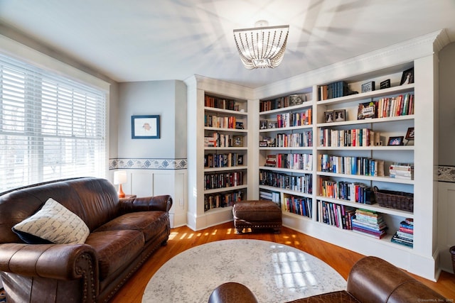 sitting room featuring hardwood / wood-style floors, built in shelves, and a chandelier