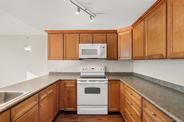 kitchen featuring white appliances, sink, dark wood-type flooring, and track lighting