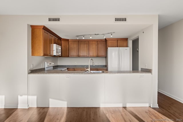 kitchen featuring hardwood / wood-style flooring, white appliances, and sink