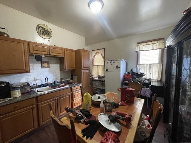 kitchen featuring decorative backsplash, white fridge, and sink