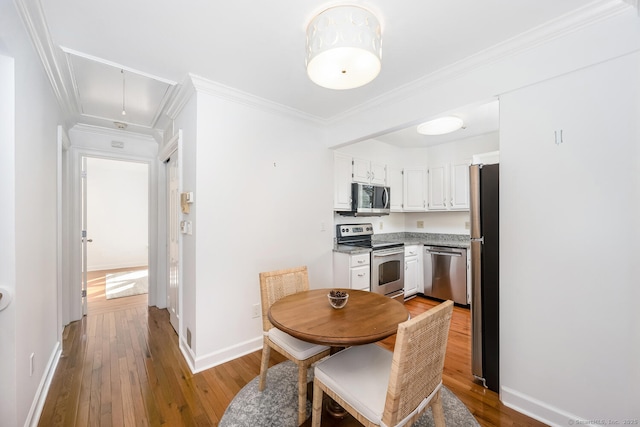 dining space with crown molding and light hardwood / wood-style flooring