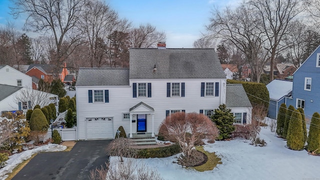 view of front facade with roof with shingles, aphalt driveway, a chimney, and an attached garage