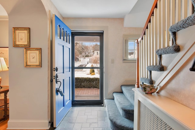 foyer entrance with a healthy amount of sunlight, stone finish flooring, stairs, and baseboards