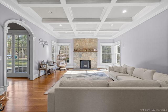 living room featuring coffered ceiling, beamed ceiling, ornamental molding, hardwood / wood-style flooring, and a fireplace