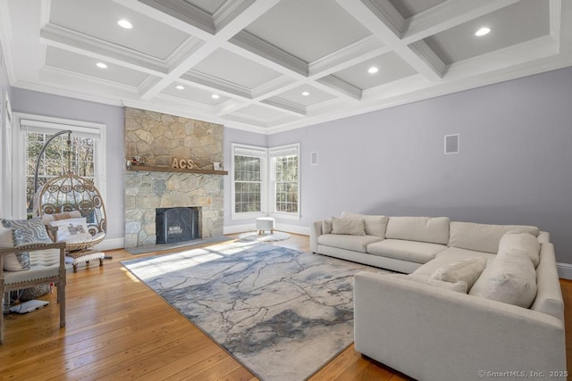 living room with beam ceiling, a healthy amount of sunlight, a fireplace, and light hardwood / wood-style floors