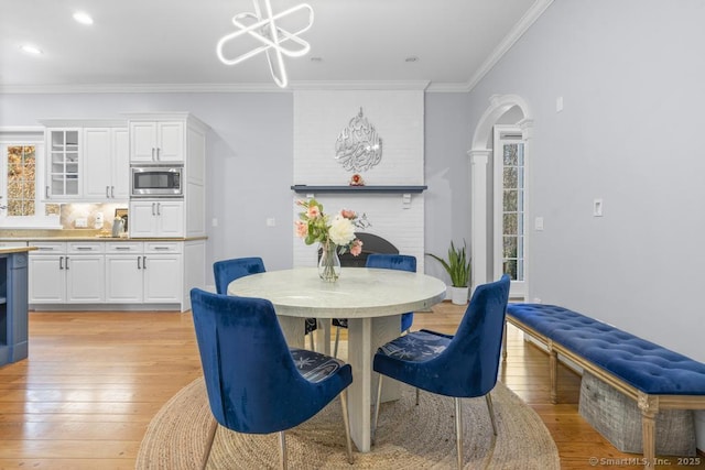 dining area with a notable chandelier, a wealth of natural light, light hardwood / wood-style flooring, and ornamental molding