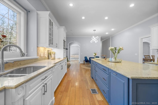 kitchen with light stone counters, sink, white cabinets, and blue cabinets