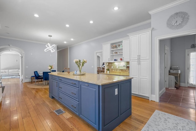 kitchen with white cabinetry, pendant lighting, an island with sink, and blue cabinets