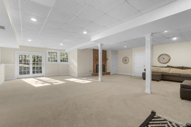 basement featuring light colored carpet, a fireplace, and a drop ceiling