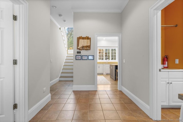 corridor featuring light tile patterned floors, ornamental molding, and sink