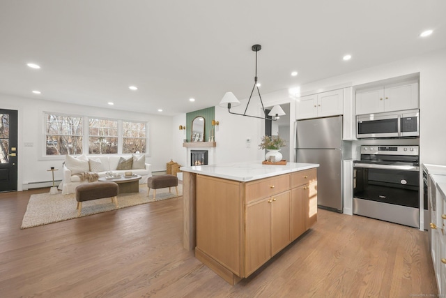 kitchen with a center island, a baseboard heating unit, decorative light fixtures, white cabinets, and appliances with stainless steel finishes