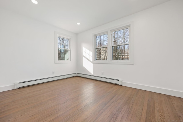 unfurnished room featuring hardwood / wood-style floors and baseboard heating