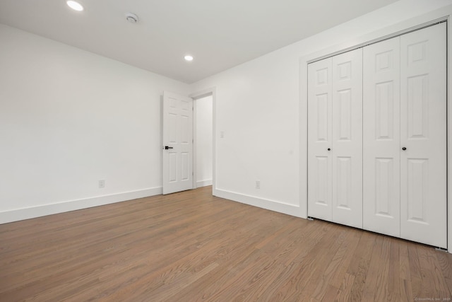 unfurnished bedroom with light wood-type flooring and a closet