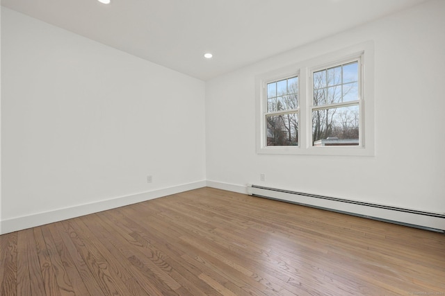 empty room with baseboard heating and light hardwood / wood-style flooring