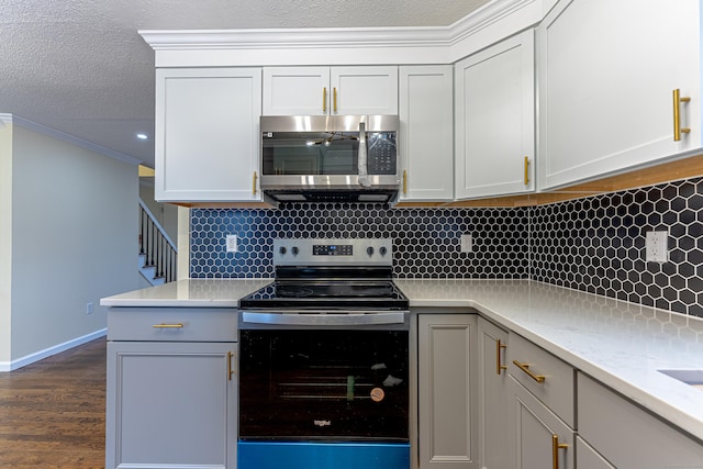 kitchen with tasteful backsplash, white cabinetry, crown molding, and stainless steel appliances