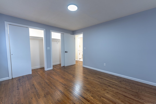 unfurnished bedroom featuring dark hardwood / wood-style flooring and two closets