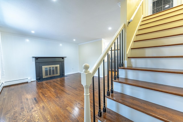 stairway with a fireplace, hardwood / wood-style floors, and ornamental molding