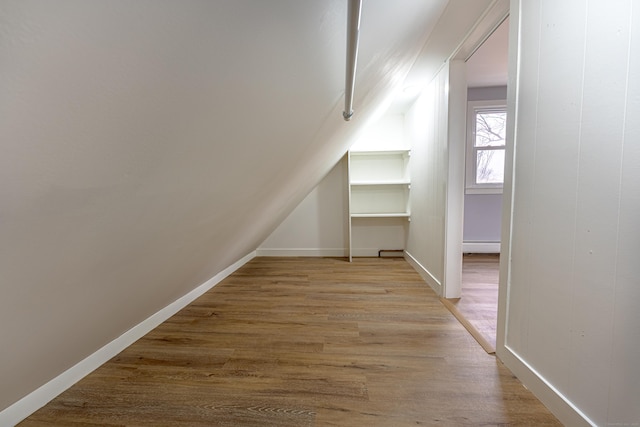 bonus room with a baseboard heating unit, lofted ceiling, and light hardwood / wood-style flooring