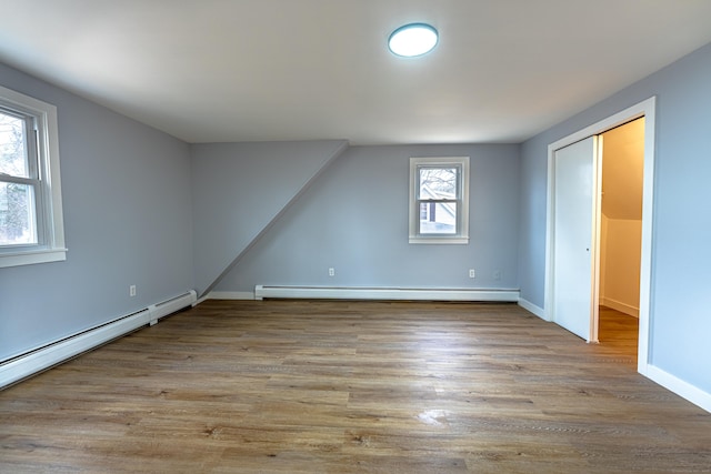 additional living space featuring light wood-type flooring, a baseboard radiator, and plenty of natural light