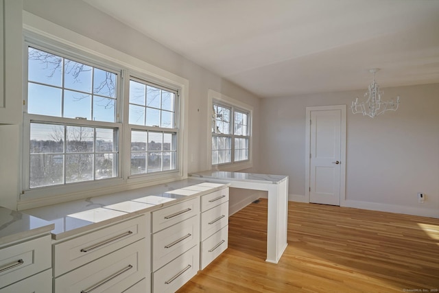 kitchen featuring white cabinets, light hardwood / wood-style flooring, decorative light fixtures, and an inviting chandelier