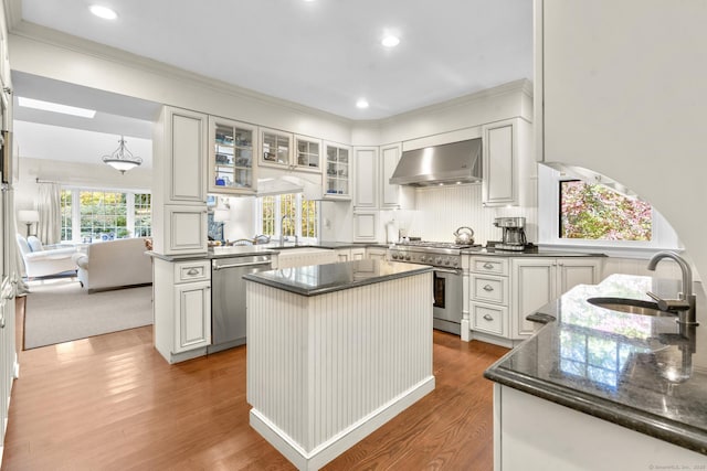 kitchen featuring white cabinets, sink, wall chimney exhaust hood, a kitchen island, and stainless steel appliances