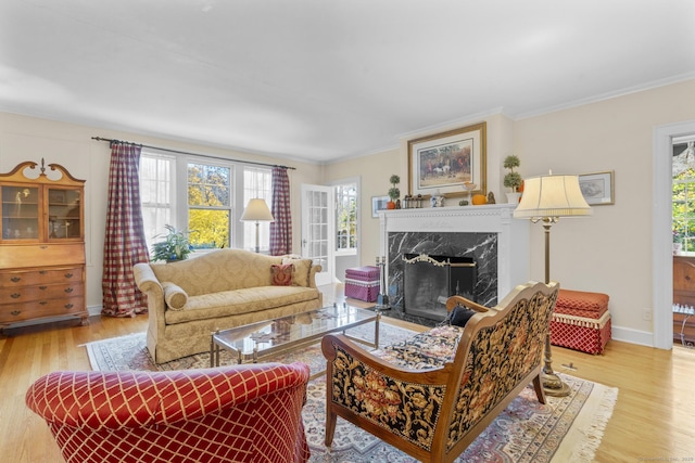 living room featuring ornamental molding, a fireplace, a healthy amount of sunlight, and light hardwood / wood-style flooring