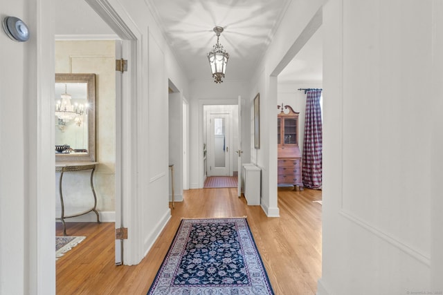 entryway with light hardwood / wood-style flooring, a chandelier, and ornamental molding