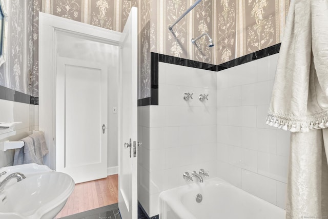 bathroom featuring wood-type flooring, tiled shower / bath combo, and sink