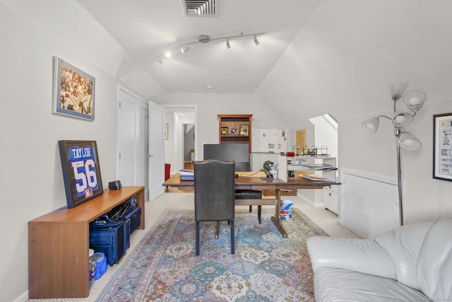 carpeted home office with track lighting and lofted ceiling