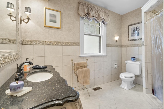 bathroom with a shower with curtain, tile patterned flooring, toilet, vanity, and tile walls