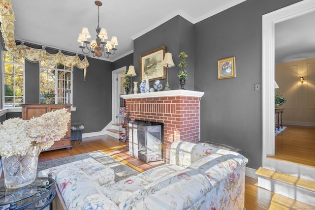 living room with an inviting chandelier, wood-type flooring, crown molding, and a brick fireplace