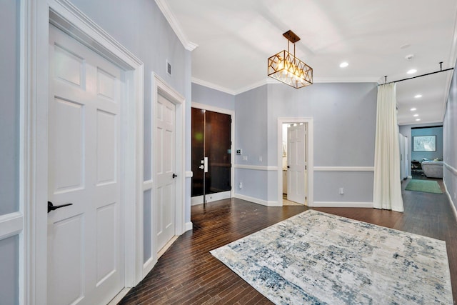 interior space featuring dark hardwood / wood-style flooring, ornamental molding, and an inviting chandelier