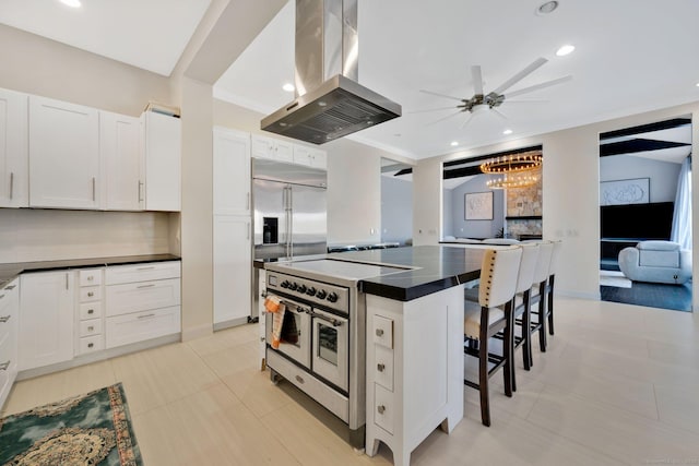 kitchen featuring white cabinets, a kitchen island, premium appliances, island range hood, and a kitchen bar