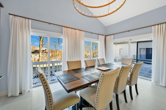 dining space with a chandelier, lofted ceiling, and light tile patterned flooring