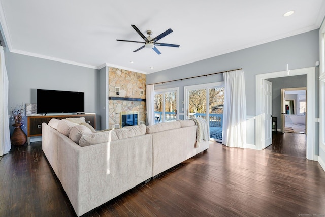 living room with a fireplace, ornamental molding, ceiling fan, and dark wood-type flooring