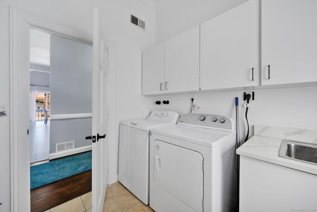 laundry area featuring cabinets, light tile patterned floors, sink, and separate washer and dryer