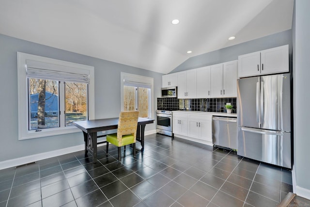 kitchen featuring appliances with stainless steel finishes, white cabinetry, lofted ceiling, and a healthy amount of sunlight