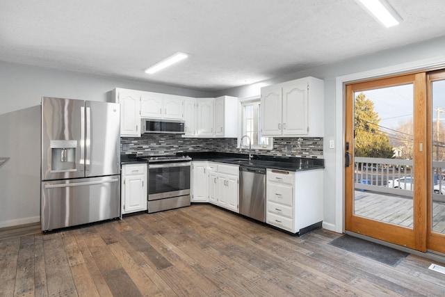 kitchen featuring stainless steel appliances, a healthy amount of sunlight, decorative backsplash, dark hardwood / wood-style flooring, and sink