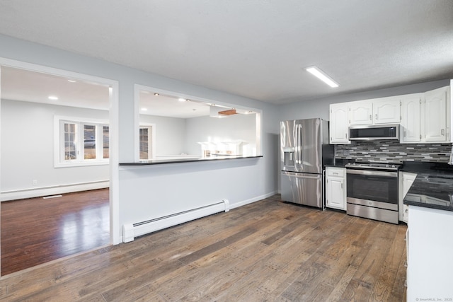 kitchen featuring white cabinetry, a baseboard heating unit, appliances with stainless steel finishes, decorative backsplash, and dark hardwood / wood-style flooring