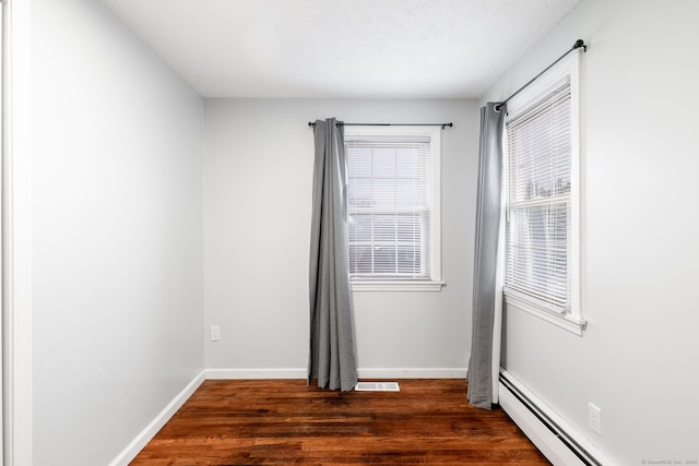 spare room featuring dark wood-type flooring and baseboard heating