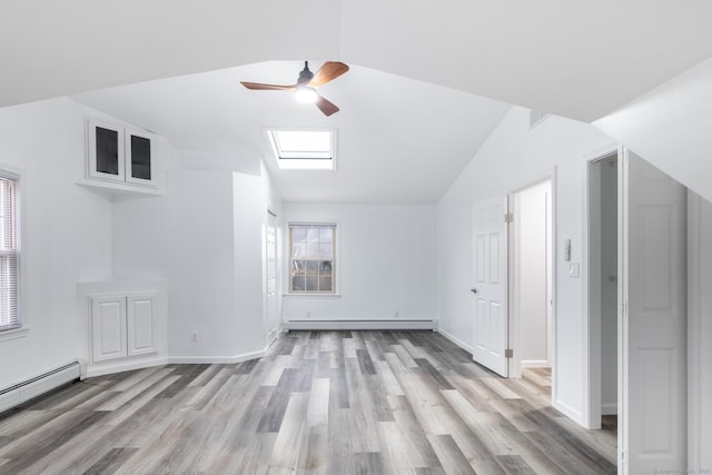 additional living space featuring ceiling fan, a baseboard radiator, lofted ceiling with skylight, and light wood-type flooring